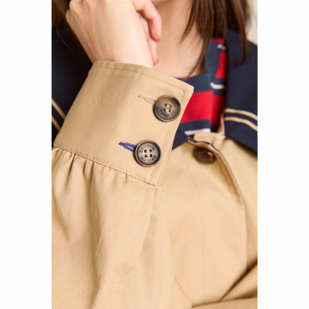 Nærbillede af ærmet på Damson Madder Ella Trench med bred beige manchet, to mørke knapper og en lille blå syningsdetalje ved det nederste knaphul.