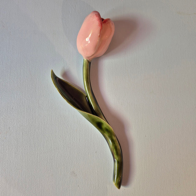 Håndlavet Odd Mud vægkunst formet som en lyserød tulipan med grøn stilk og blad på lys baggrund.