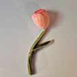 Håndlavet Odd Mud vægkunst formet som en lyserød tulipan med grøn stilk og blad på lys baggrund.