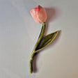 Håndlavet Odd Mud vægkunst formet som en lyserød tulipan med grøn stilk og blad på lys baggrund.