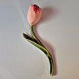 Håndlavet Odd Mud vægkunst formet som en lyserød tulipan med rødlige detaljer, grøn stilk og langt blad på lys baggrund.