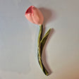 Håndlavet Odd Mud vægkunst formet som en lyserød tulipan med rødlige detaljer, grøn stilk og blad på lys baggrund.