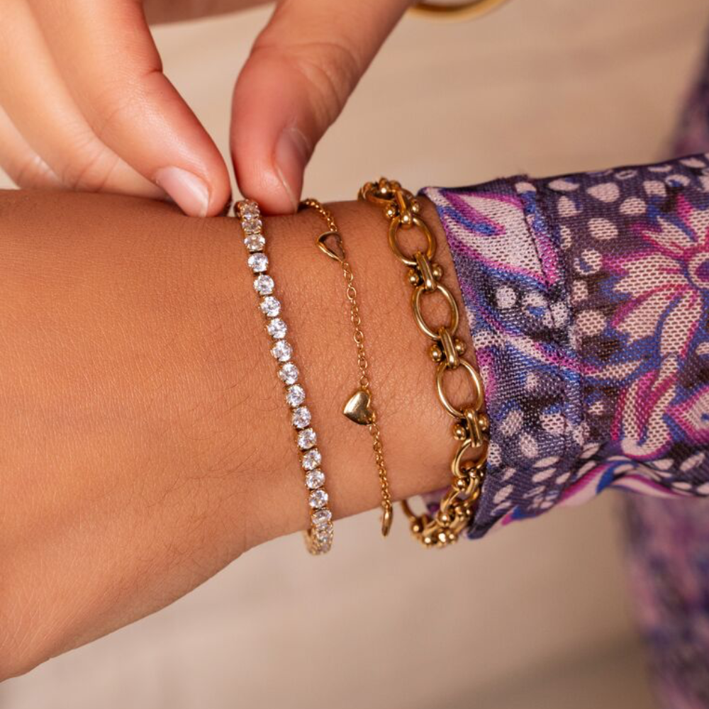 Viser guldarmbåndet med hjerter fra My Jewellery på model sammen med to andre armbånd.