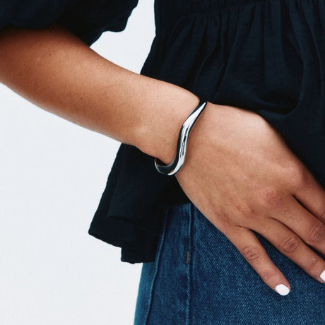 Nærbillede af Edblad Azura Bangle i stål, der viser armbåndets glatte overflade