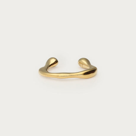 Guldfarvet lille earcuff i organisk form, fotograferet som produktbillede på lys baggrund