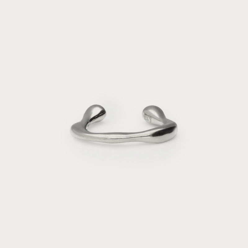 Sølvfarvet lille earcuff i organisk form, fotograferet som produktbillede på lys baggrund