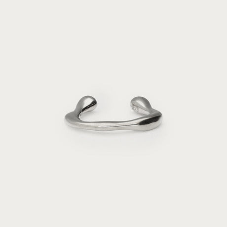Sølvfarvet lille earcuff i organisk form, fotograferet som produktbillede på lys baggrund