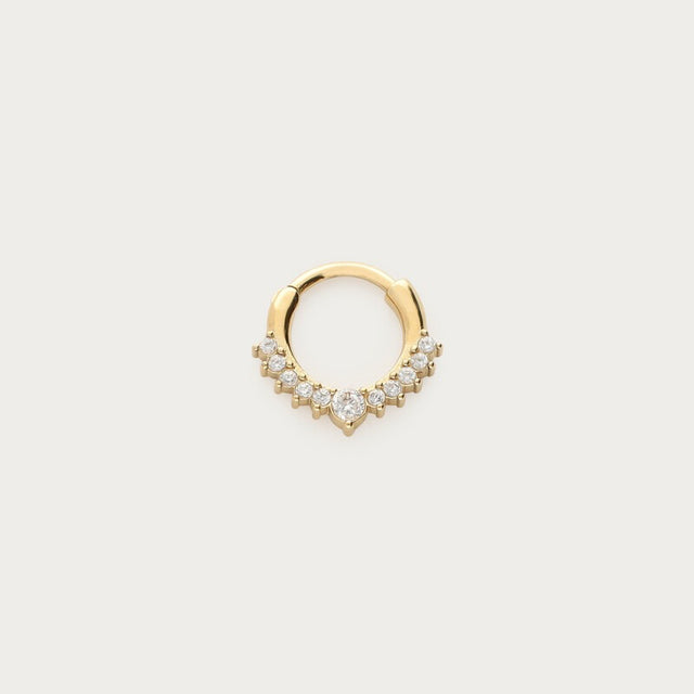 Guldfarvet daith-piercing med skarpt design og strass, fotograferet som produktbillede på lys baggrund
