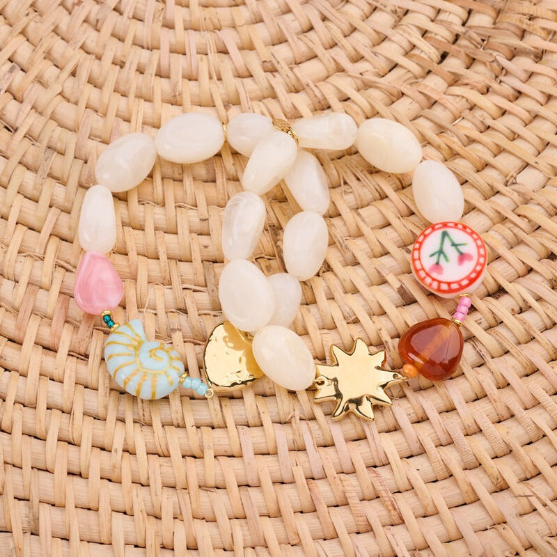 Stylet opstilling med flere guldfarvede armbånd og farverige resin-charms