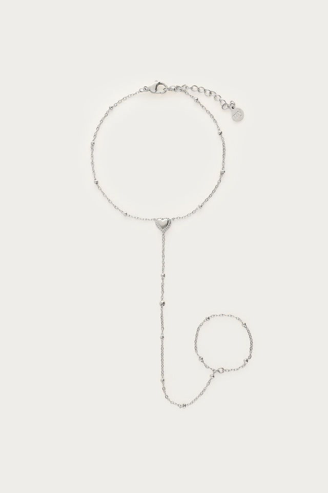 Sølvfarvet handchain-armbånd med hjertevedhæng, fotograferet som produktbillede på lys baggrund