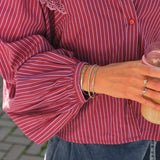 Sølvfarvet My Jewellery bangle-armbånd med vintage blomstermønster båret af en model sammen med to andre armbånd. 